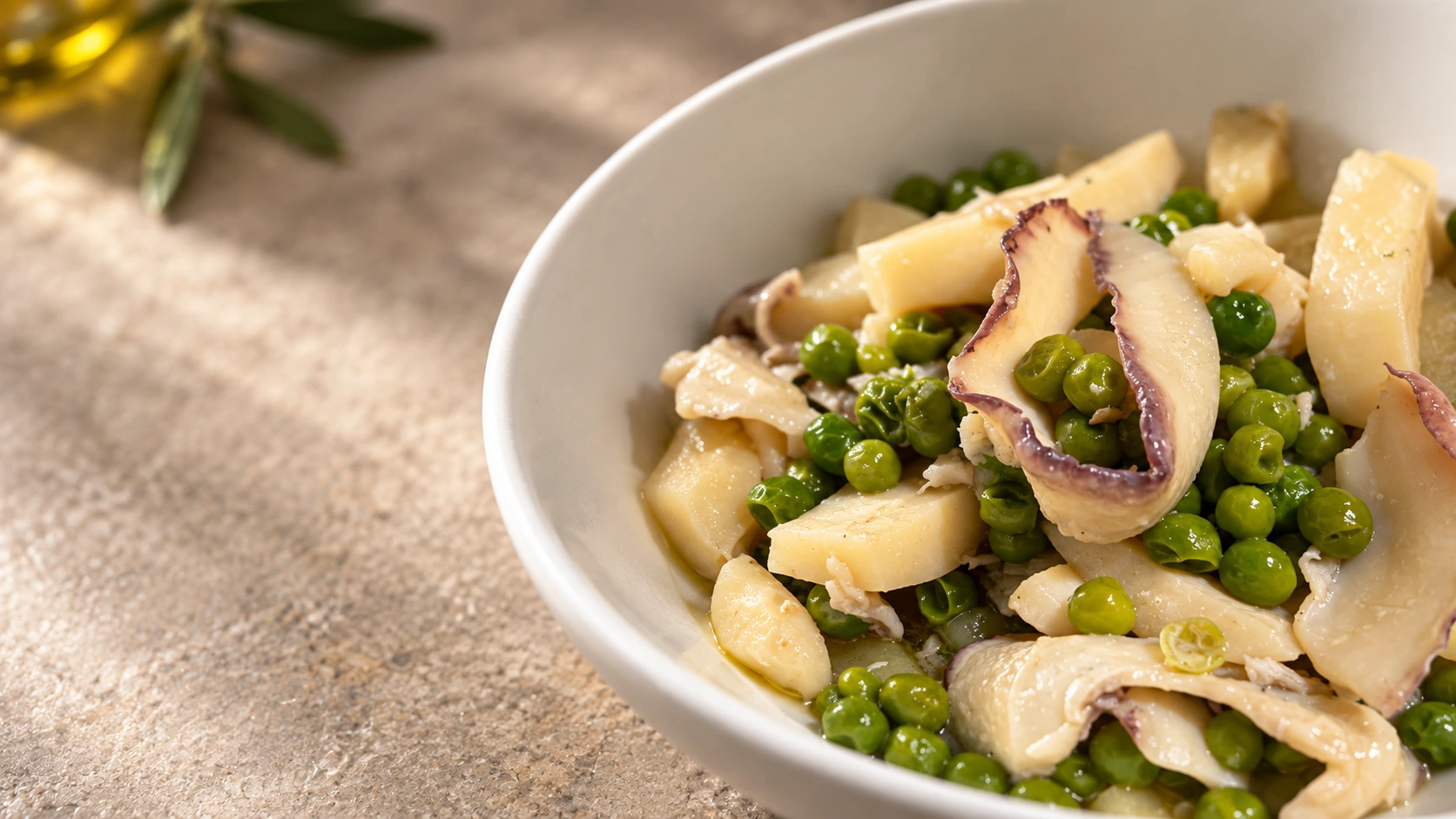 Cuttlefish with peas served in a plain white ceramic dish.